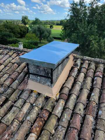 Réparation d’une cheminée en zinc avec chapeau sur mesure et entourage bétonné près de Bergerac